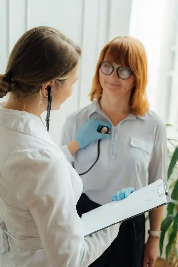 Doctor listens to a patient's heartbeat with a stethoscope in a bright room. - dpc and health insurance
