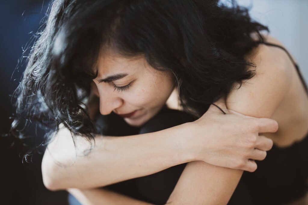 woman holding self, looking down - hidden costs of chronic stress