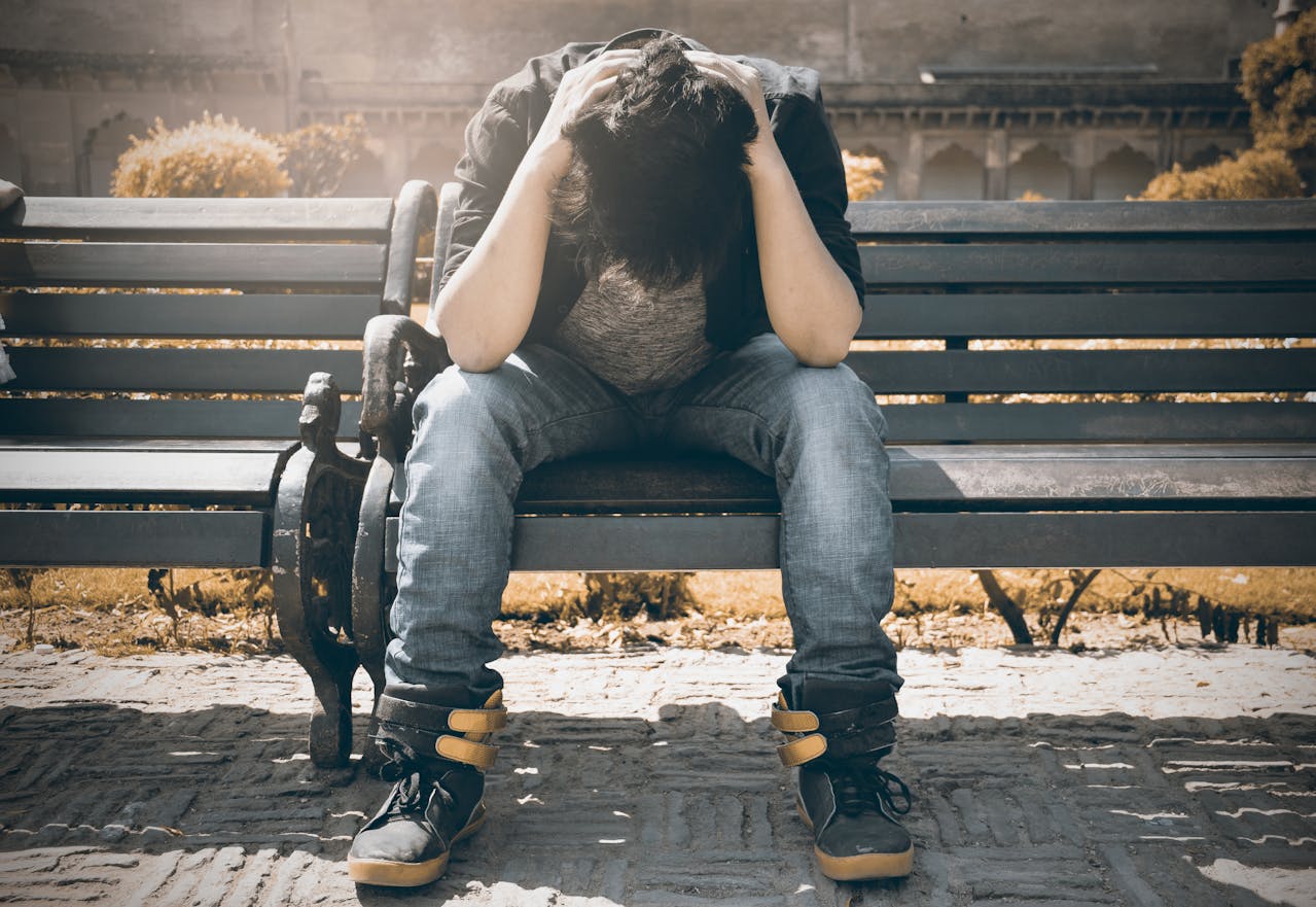 stressed man sitting on park bench - hidden costs of chronic stress