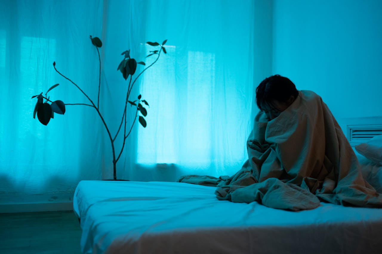 person wrapped in blanket sitting on bed - rethinking mental health