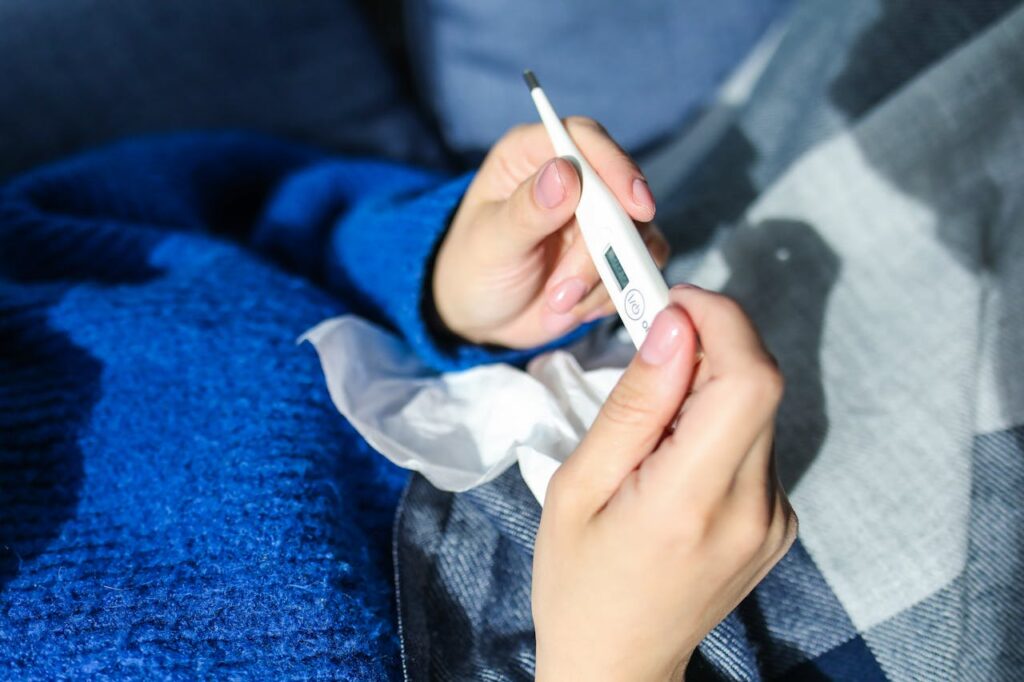 person checking thermometer - infections when to seek medical care