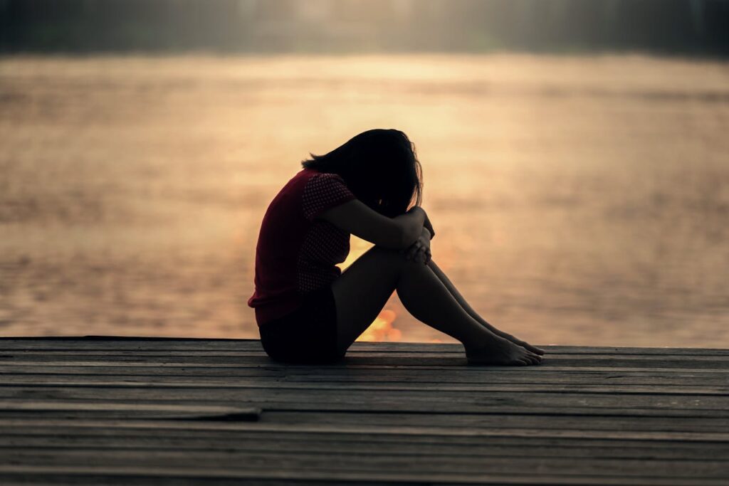 woman resting head on knees - Burnout vs. Depression
