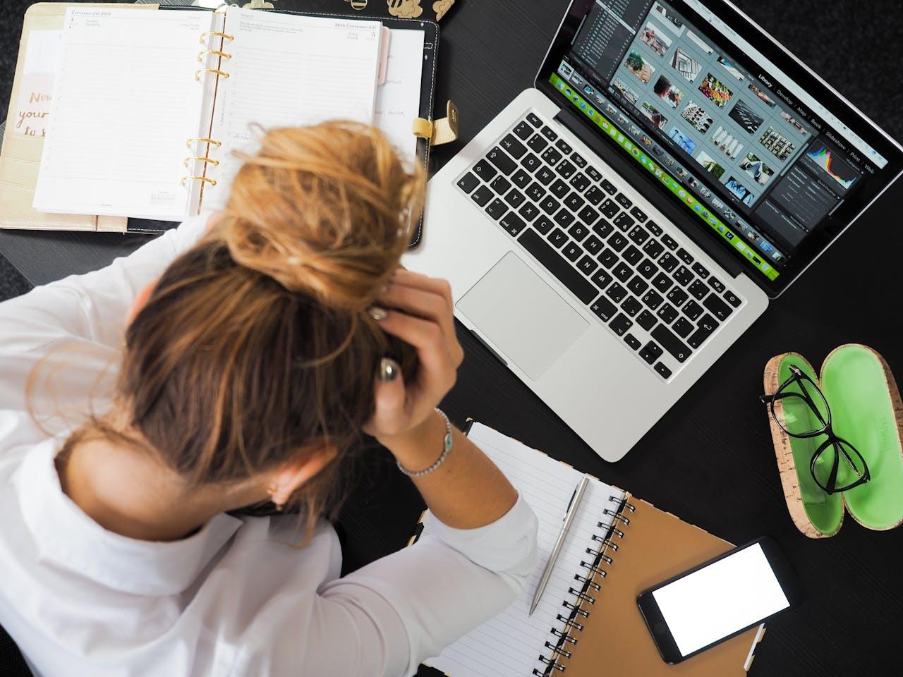 stressed woman in front of laptop, notes, and phone