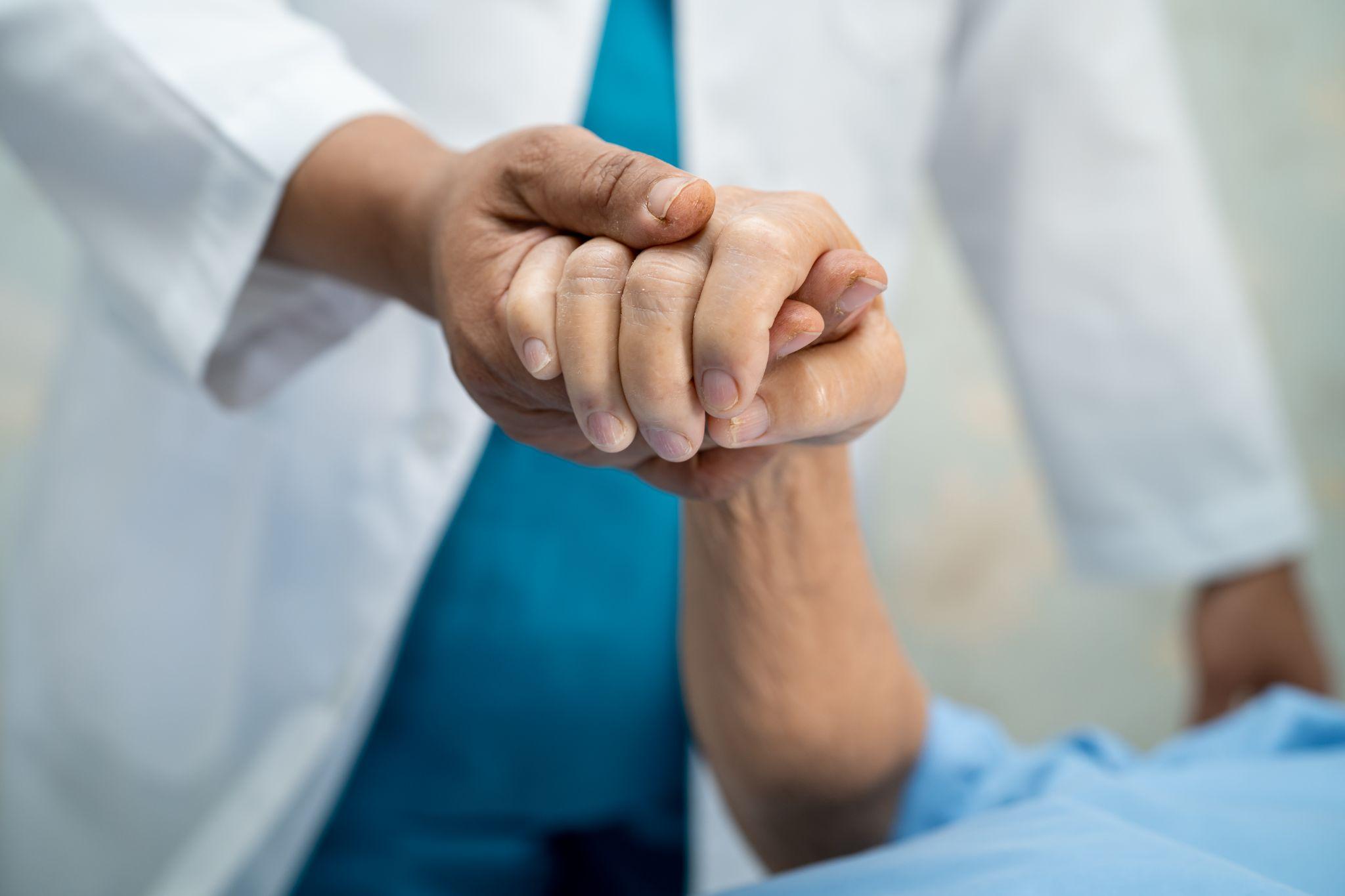 doctor holding patient’s hand, showing empathy and care