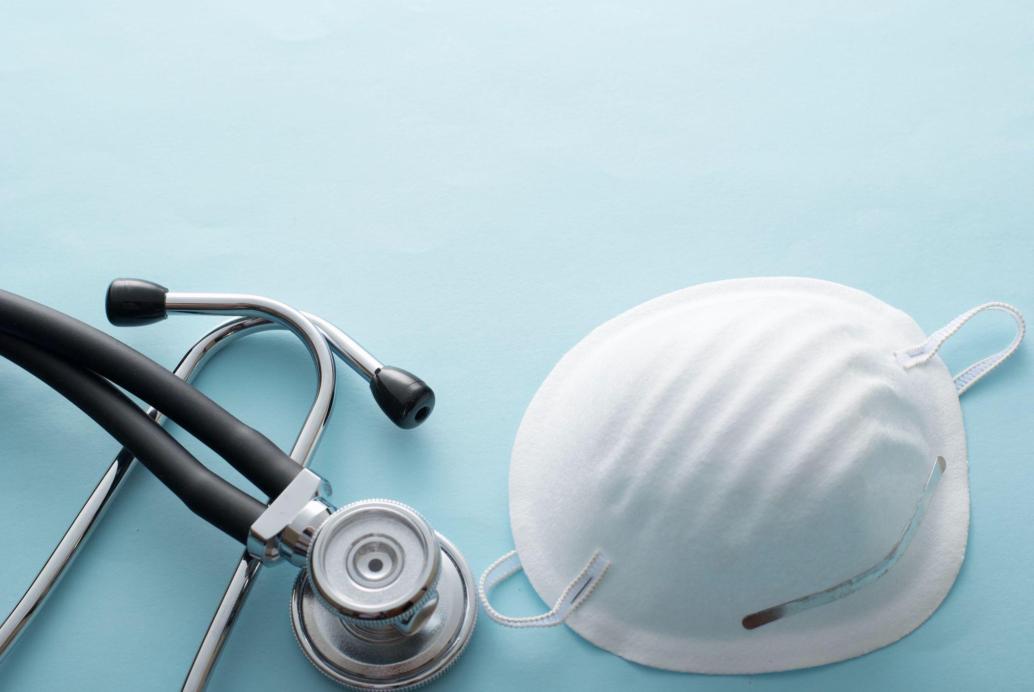 face mask and stethoscope on blue surface