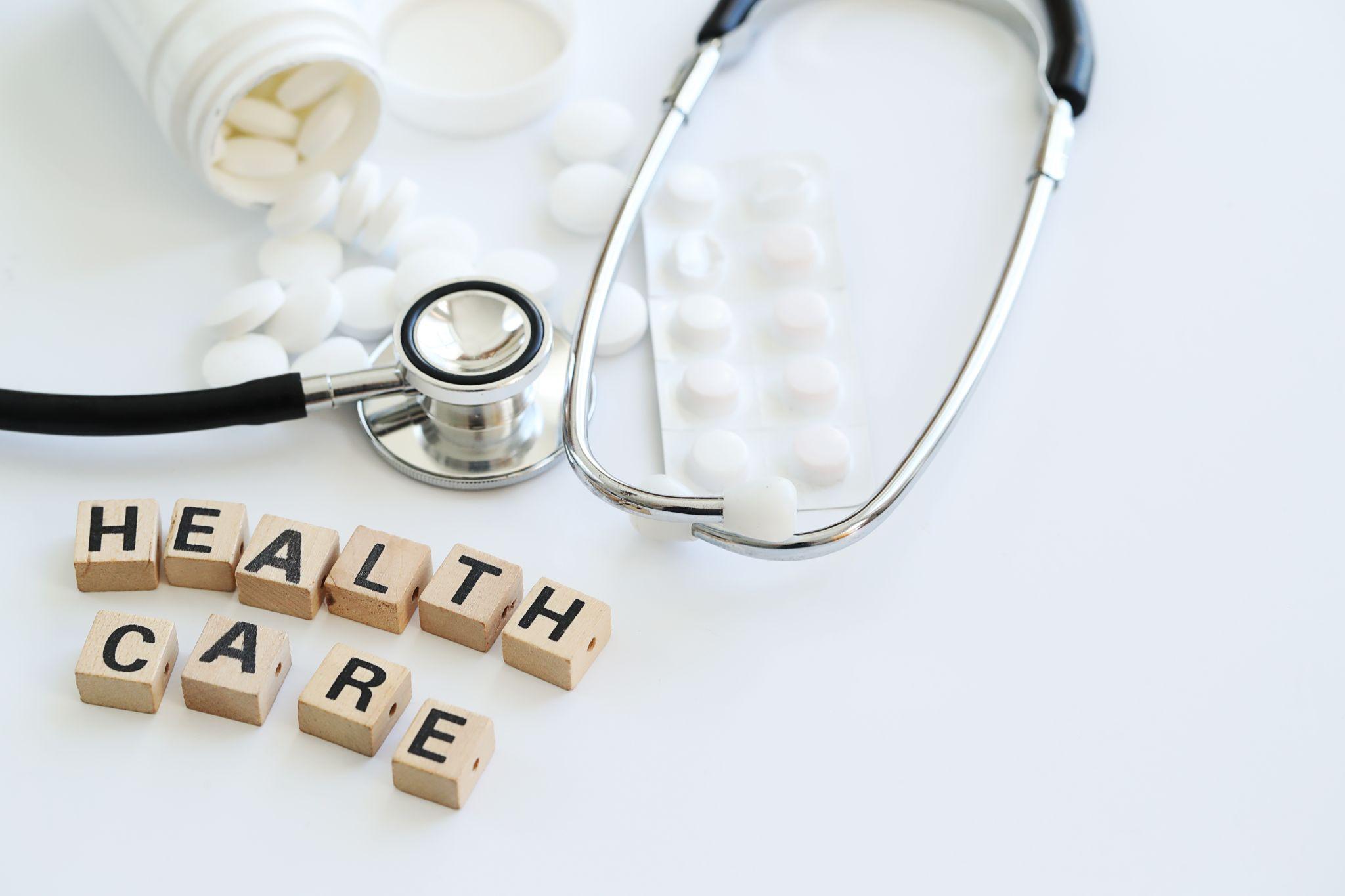stethoscope, medicine, and blocks spelling out “healthcare”