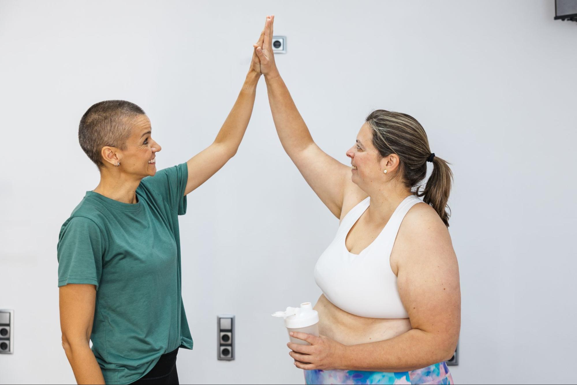 Personal trainer and nutritionist giving high five to client after successful workout