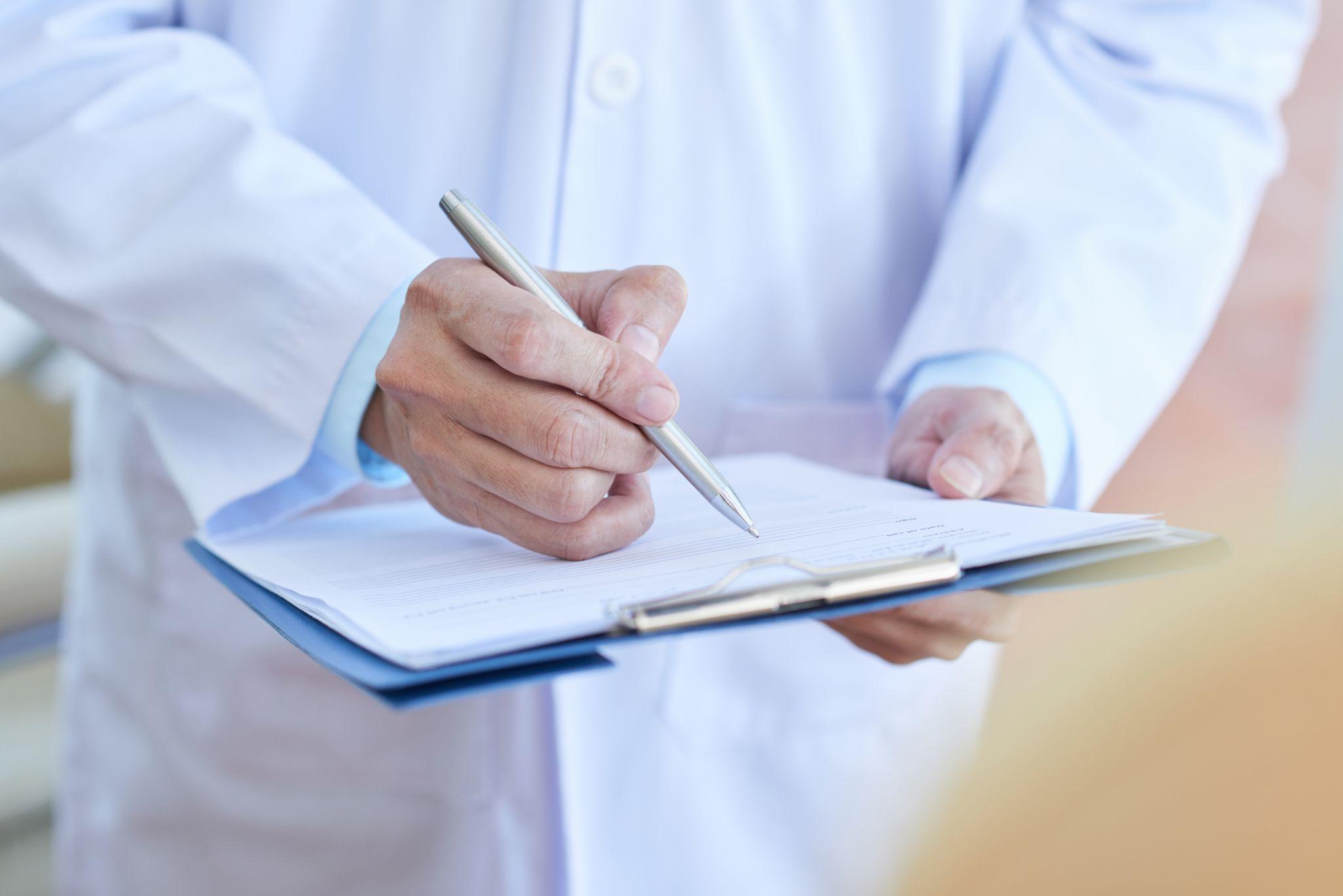 doctor writing notes on clipboard