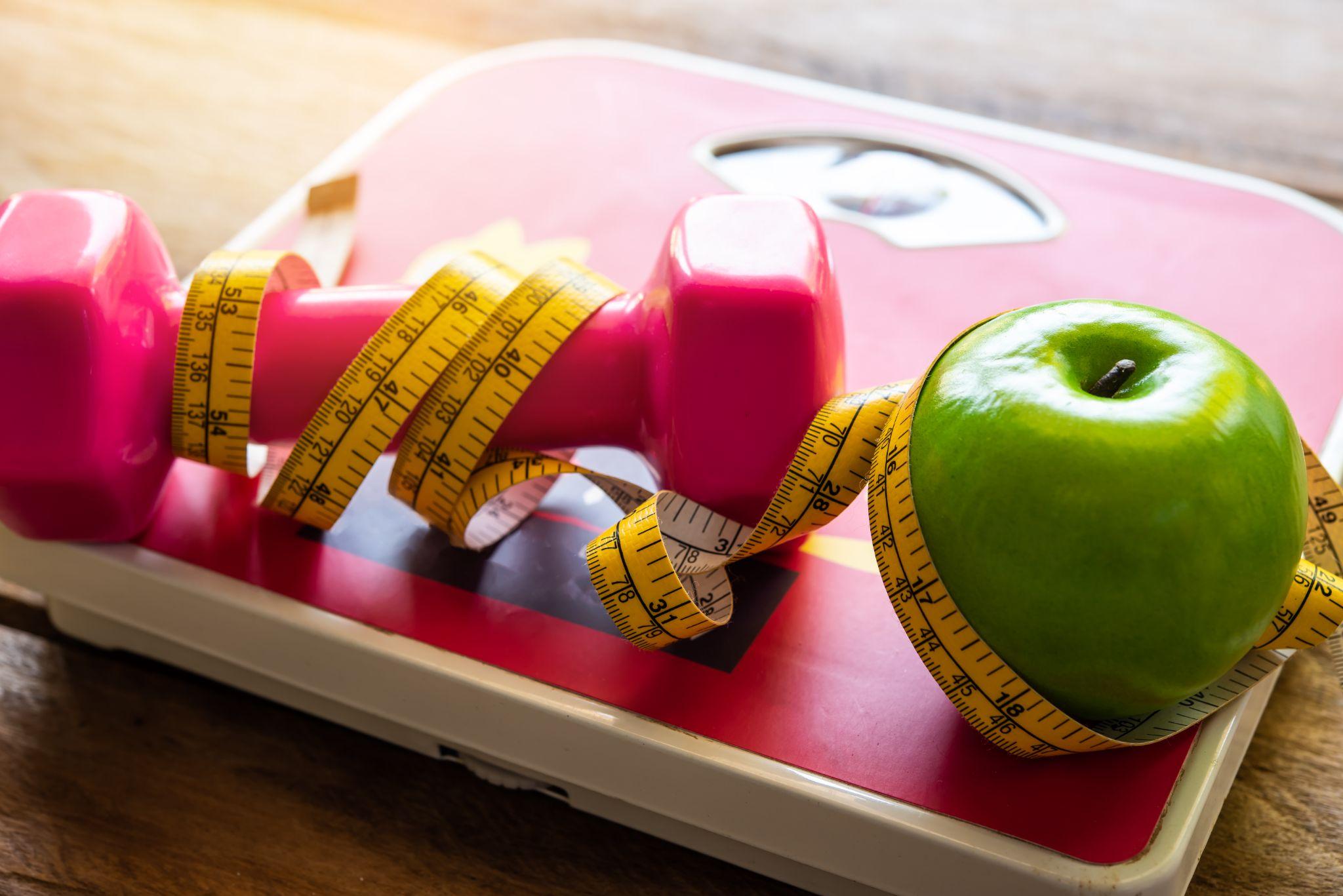 Flat lay of exercise equipment on wooden background representing fitness and weight loss