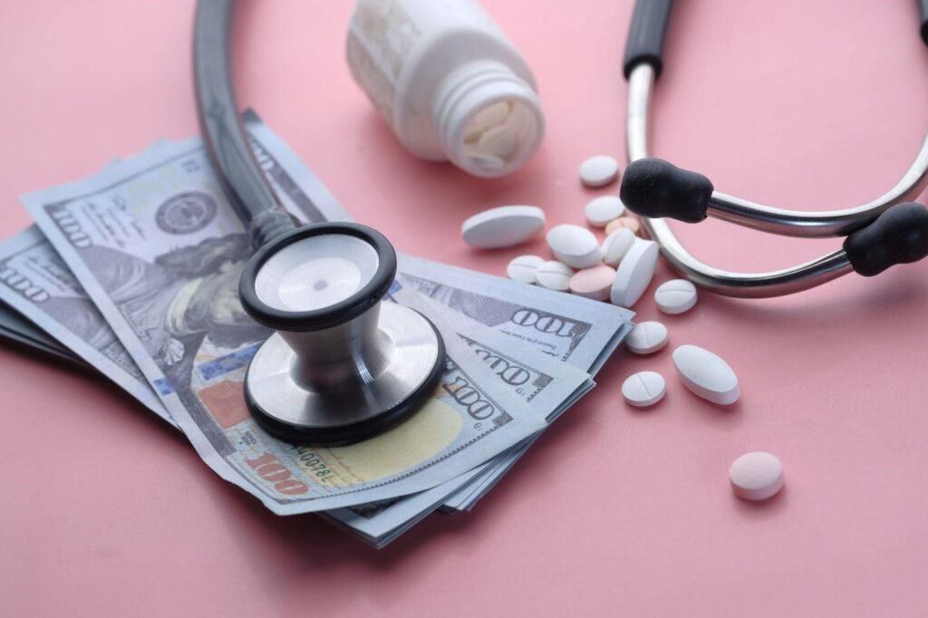 Stethoscope, cash, and medicine tablets symbolizing affordable healthcare with a no insurance doctor in North Houston, TX.