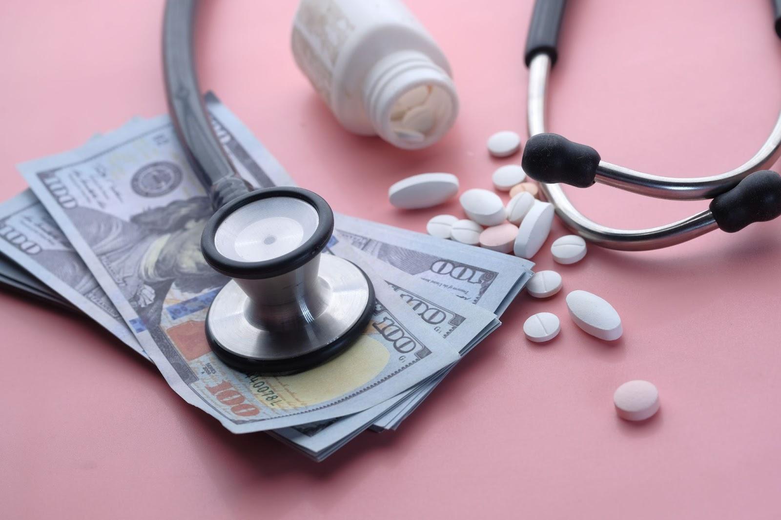 Stethoscope, cash, and medicine tablets symbolizing affordable healthcare with a no insurance doctor in North Houston, TX.